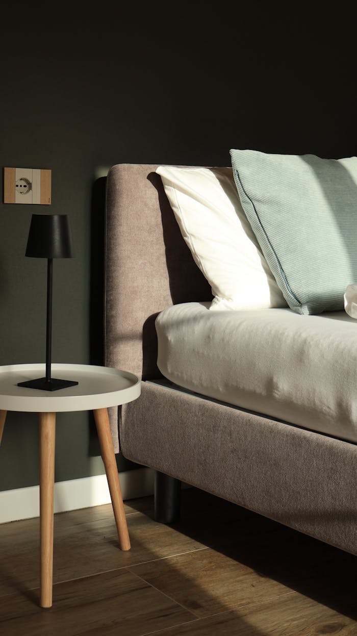 A minimalist bedroom featuring a stylish upholstered bed and sleek side table with lamp.